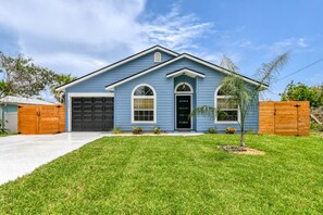 A single-story house with a garage, a front yard, and a wooden fence.