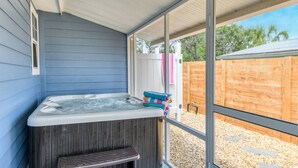 Egy fedett, szabadtéri területen található jakuzzi, ahonnan egy fa kerítésre és fákra nyílik kilátás.