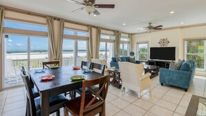 A spacious living room with a large TV, comfortable seating, and a balcony with a view of the beach. - A Pirate's Paradise (St. Augustine)