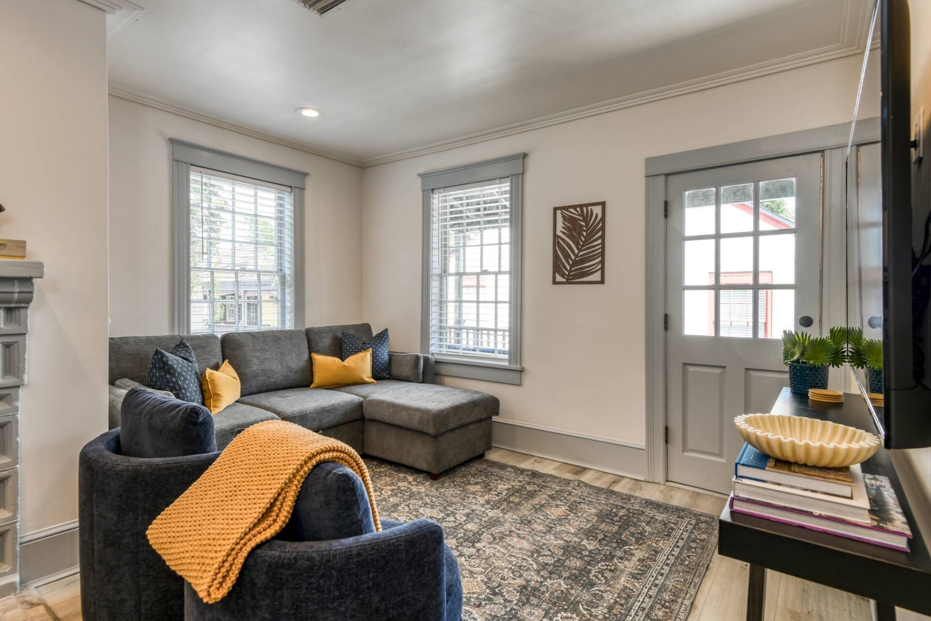 A living room with a sectional sofa, a small armchair, a fireplace, and a door with a window.