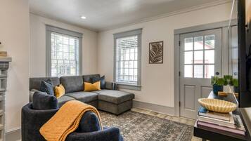 A living room with a sectional sofa, a small armchair, a fireplace, and a door with a window.