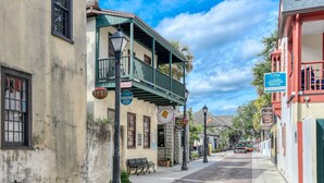 Una calle estrecha flanqueada por edificios, incluyendo un hotel boutique con balcón y un letrero que indica que es un alquiler vacacional de lujo.