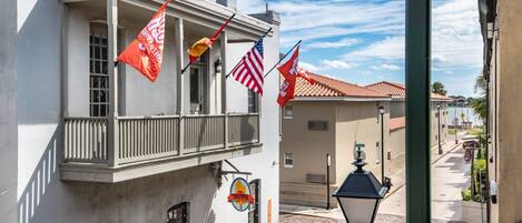 A building with a balcony, flags, and a street lamp.