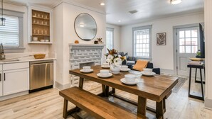 Una cocina moderna con armarios blancos, una mesa de comedor de madera y un horno empotrado.
