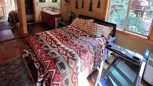 A bedroom with a bed, a desk, a window with a view of trees, and a wooden ceiling. - Truckee Mountain Retreat + Trails + Pet Friendly (Truckee)