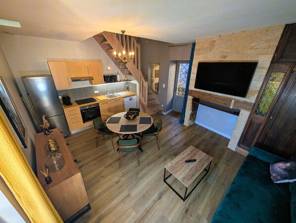 Une cuisine moderne avec des meubles en bois, un four encastré et un coin repas comprenant une table ronde et des chaises.