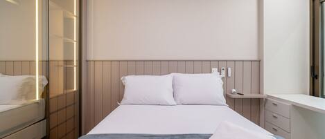 A modern bedroom with a bed, bedside table, and a wardrobe with a mirror.