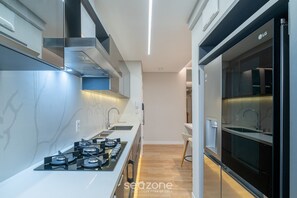 A modern kitchen with a gas stove, a built-in oven, and a microwave. - Apart w/ 2 Suites in Jurere Internacional Vvc0202 (Florianópolis)