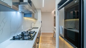 A modern kitchen with a gas stove, stainless steel appliances, and a built-in oven. - Apart w/ 2 Suites in Jurere Internacional Vvc0202 (Florianópolis)
