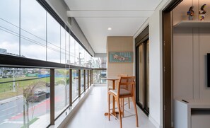 Un balcon moderne donnant sur une rue de la ville, une table à manger avec des chaises et un menu fixé au mur.