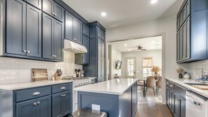 Una cocina moderna con armarios azul oscuro, encimera blanca y electrodomésticos de acero inoxidable.