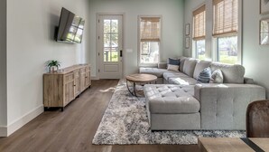 Una sala moderna con un sofá modular, una mesa de centro y un televisor montado en la pared.