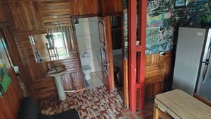 A compact kitchen with a sink, a refrigerator, and a patterned floor. - Monteverde Monkey Hostel (Monteverde)