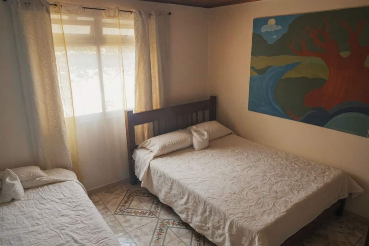 Un dormitorio con una cama, una cama individual y una ventana con cortinas.