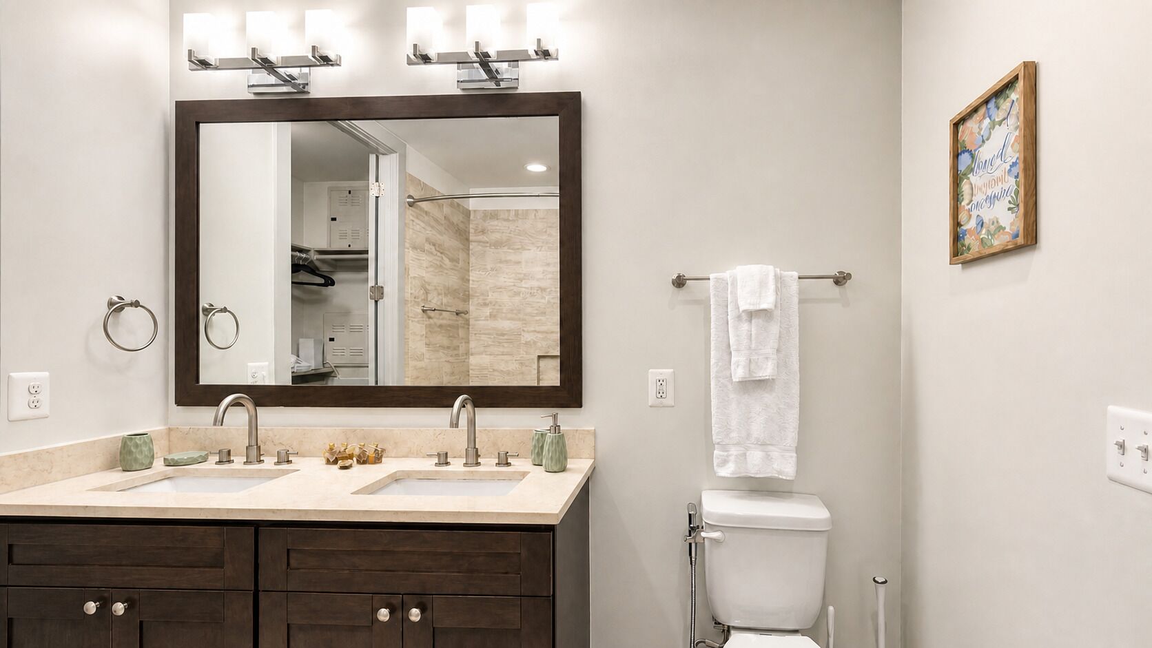 A bathroom with a double sink, a large mirror, a towel rack, and a toilet.