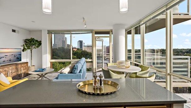 Een moderne keuken met een groot eiland, een eethoek met een ronde tafel, en een zithoek met een bank en stoelen.