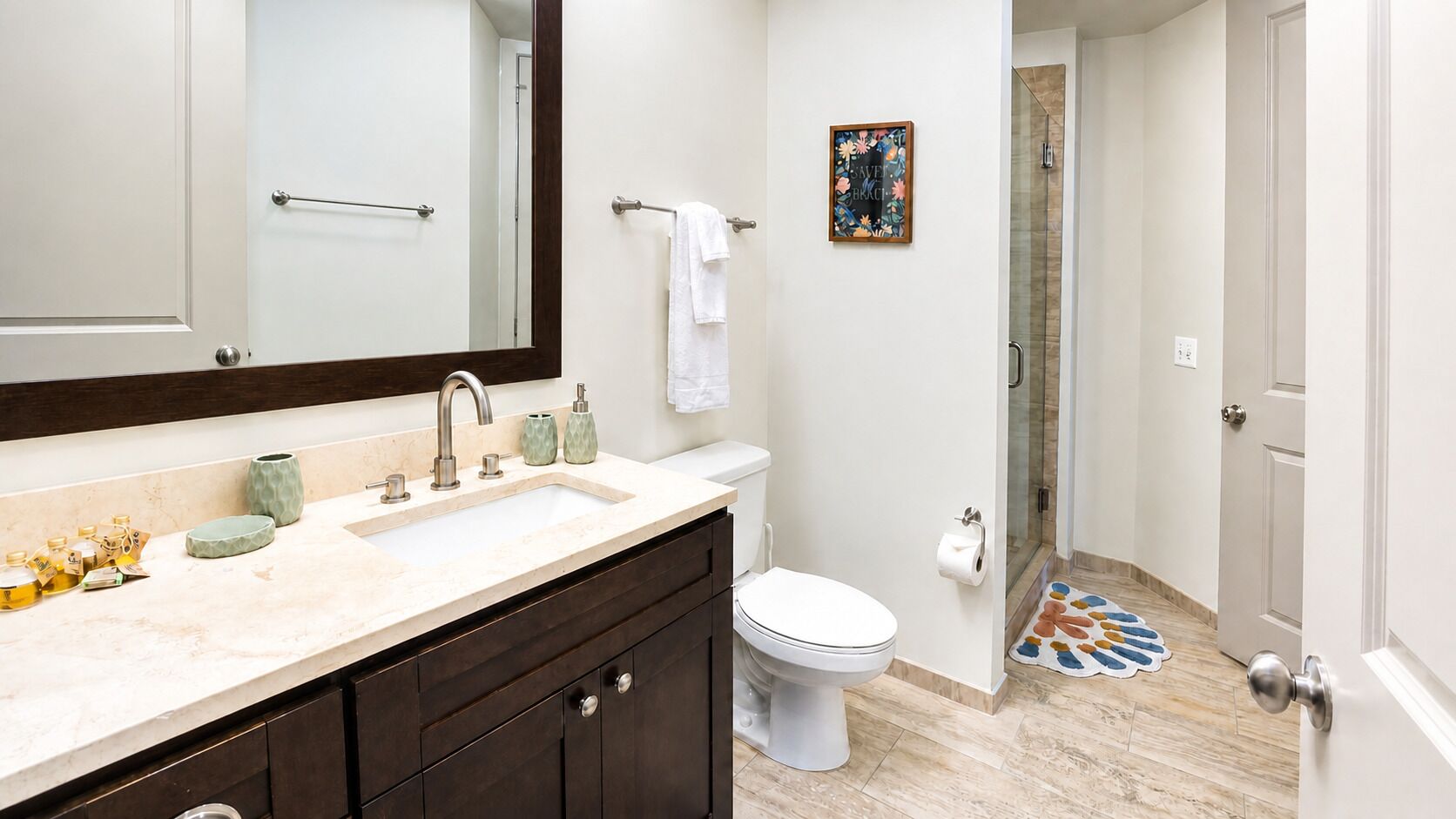 Une salle de bain équipée d’un lavabo, d’un miroir, de toilettes et d’un espace douche.