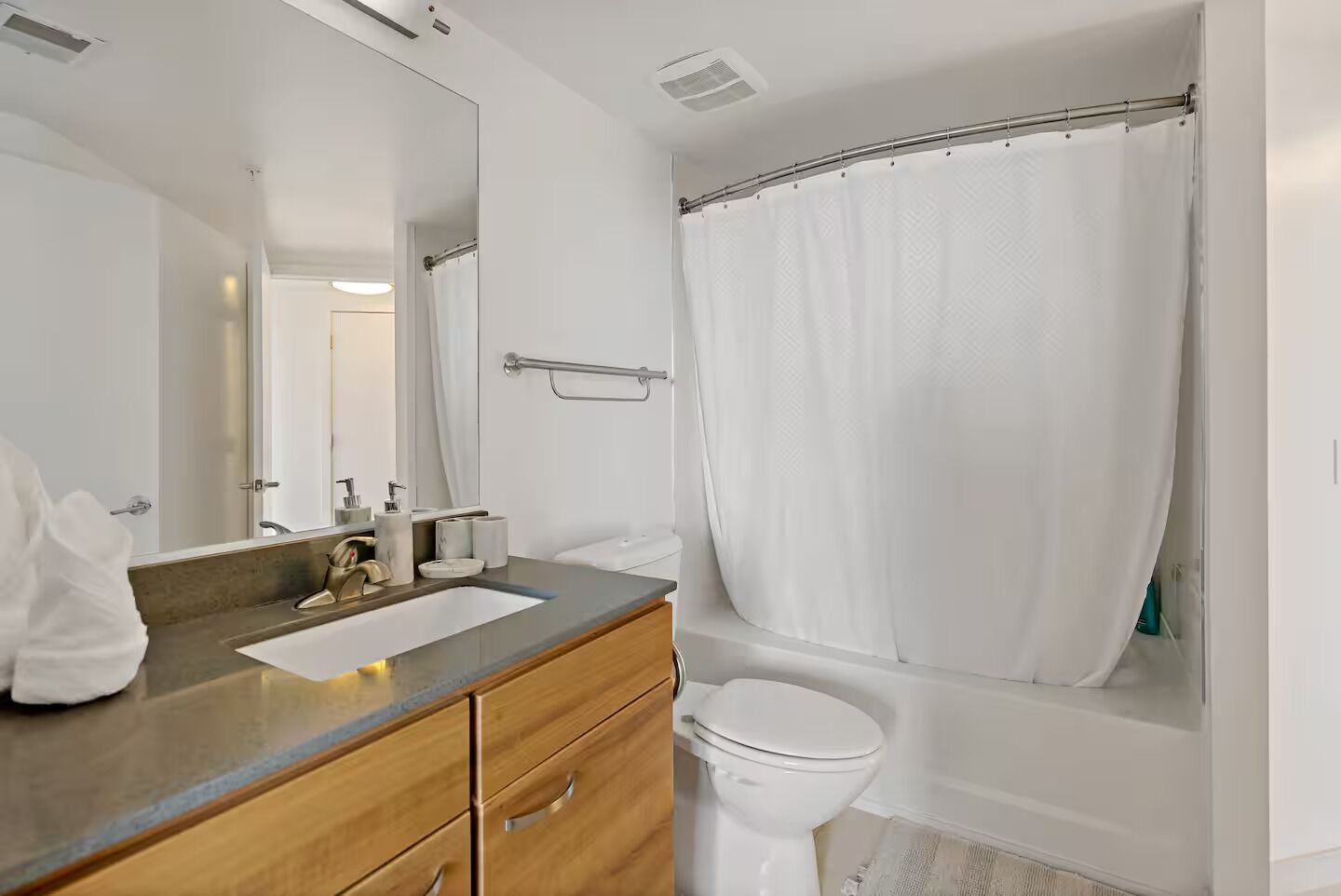 Et moderne badeværelse med vask, spejl og toilet.