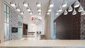 Een moderne hotel lobby met een receptiebalie, behang met een patroon en zitplaatsen met geometrische patronen.