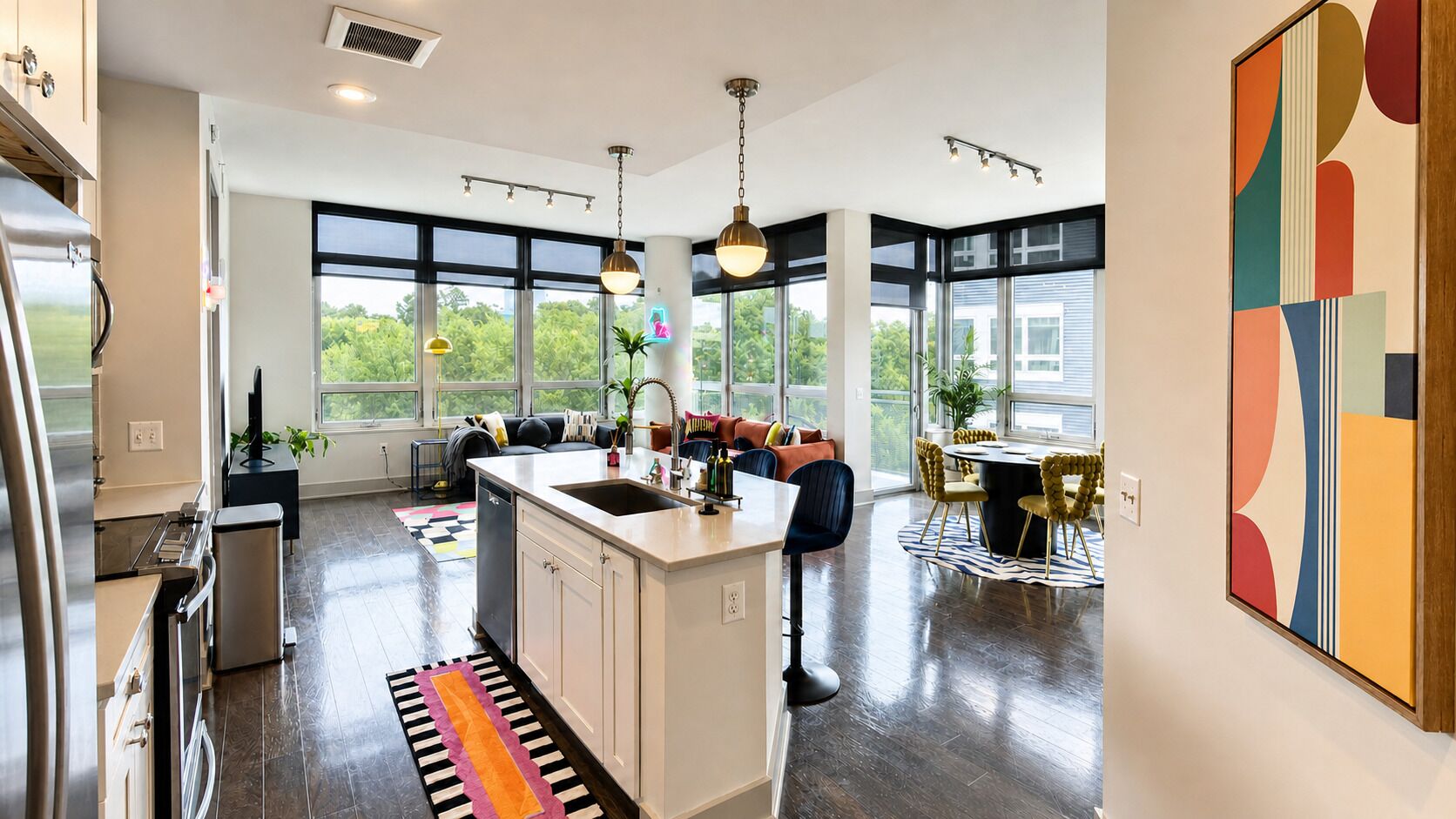 A modern kitchen with a central island, large windows, and a dining area with a round table.