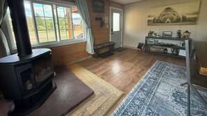 A room with a wood-burning stove, a bench, a rug, and a ceiling fan.