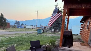 A patio with outdoor furniture, an American flag, and a wooden cabin structure.