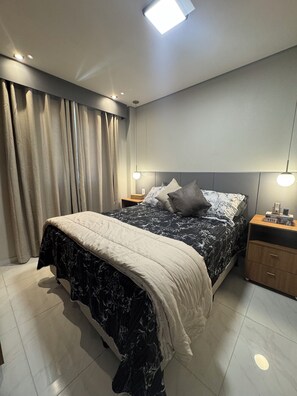 A modern bedroom with a large bed, a nightstand, and a bedside table. - Futuro Beach Apartment (Fortaleza)