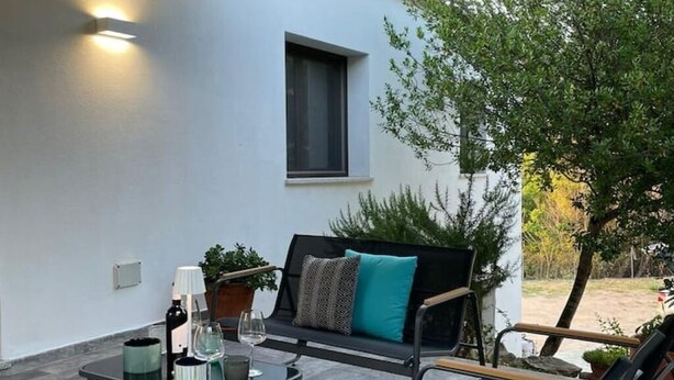 Ein moderner Sitzbereich im Freien mit einer Couch, Sesseln und einem Tisch.