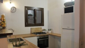 Eine kleine Küche mit Herd, Backofen, Spüle und einer Uhr an der Wand.
