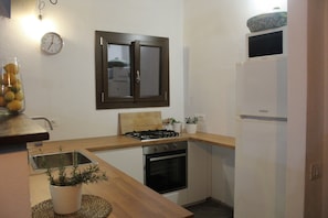 A compact kitchen with a stove, oven, sink, and a clock on the wall.