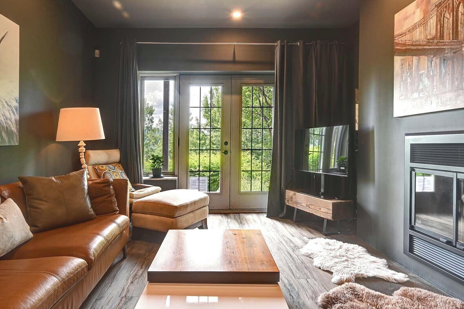 A modern living room with a leather sofa, a coffee table, a fireplace, and a television.