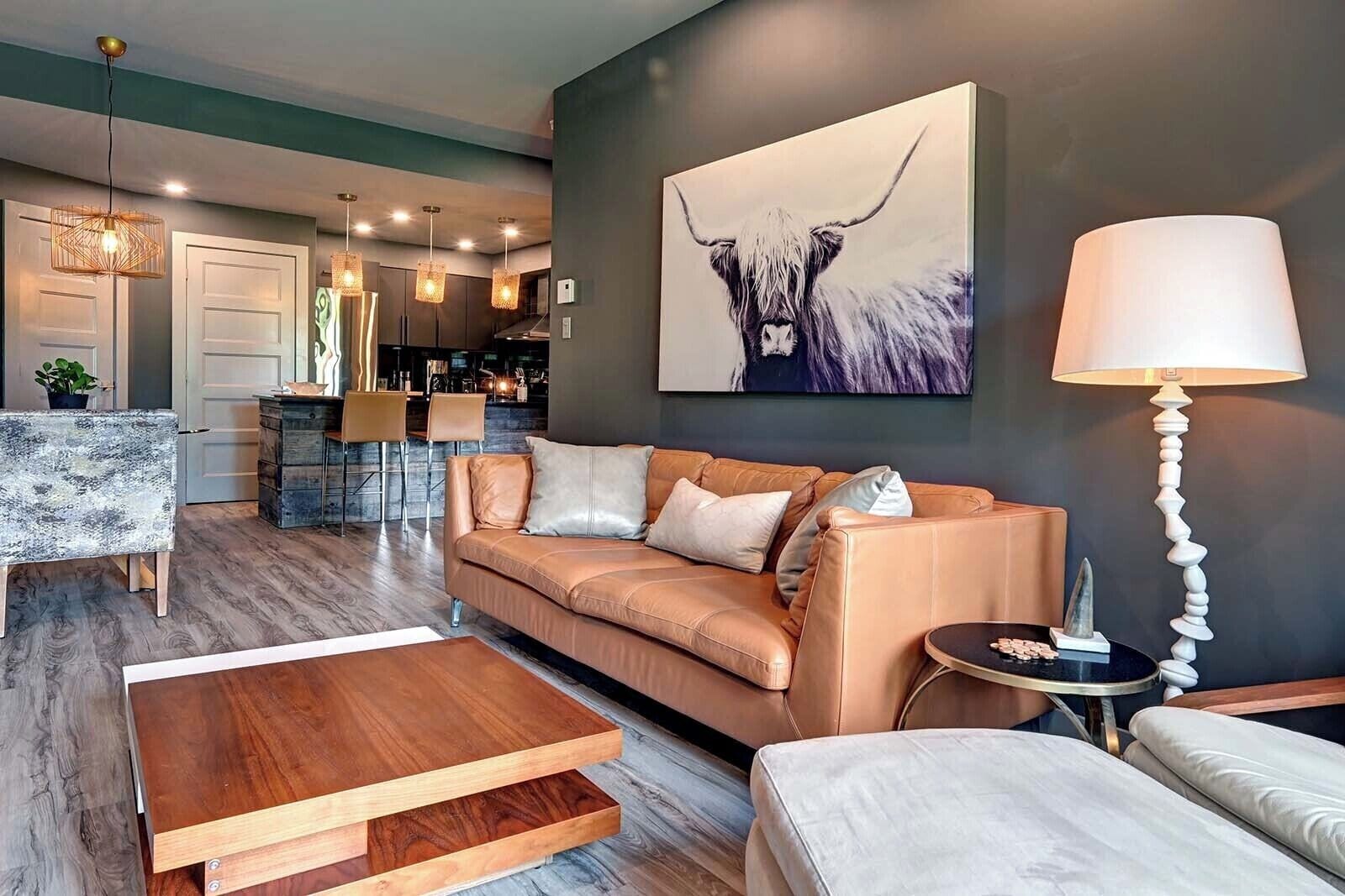 A modern living room with a sofa, coffee table, and a painting of a bull.