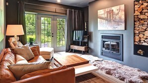 A cozy living room with a leather sofa, a wooden coffee table, and a fireplace. - 120 Algonquin Unit 7 (Mont-Tremblant)