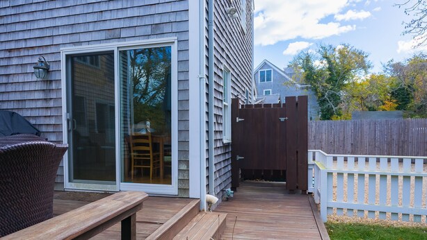 A wooden deck with a bench, a sliding glass door, and a white picket fence. - Edgartown Escape – Walk to Beach & Downtown (Edgartown)