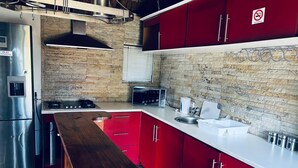Una cocina moderna con armarios rojos, un refrigerador de acero inoxidable y una encimera de madera.