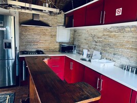 Una cocina moderna con armarios rojos, un refrigerador de acero inoxidable y una encimera de madera.