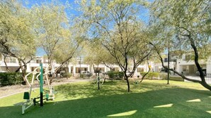 A park with exercise equipment, green grass, and trees. - Family House w/Alberca 5 min Airport/Consulate (Hermosillo)
