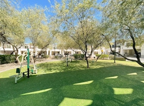 Un parco con attrezzature per l'esercizio fisico, prato verde e alberi.