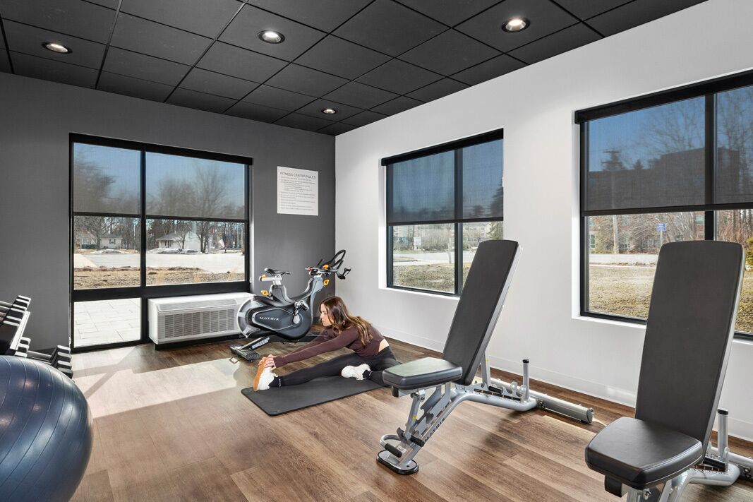 Une salle de sport équipée de matériel d’exercice, dotée de grandes fenêtres et offrant une vue sur l’extérieur.
