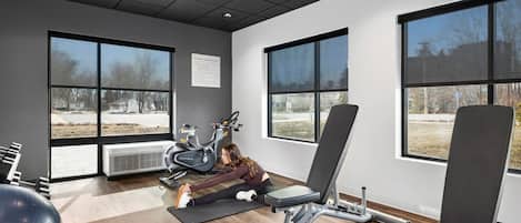 Una palestra con attrezzature per esercizi, ampie finestre e vista esterna.