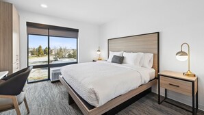 Quarto de hotel moderno com uma cama grande, uma escrivaninha e vista para o exterior.