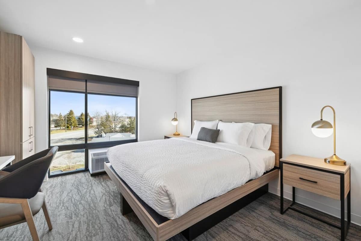 Habitación de hotel moderna con una cama grande, un escritorio y vistas al exterior.