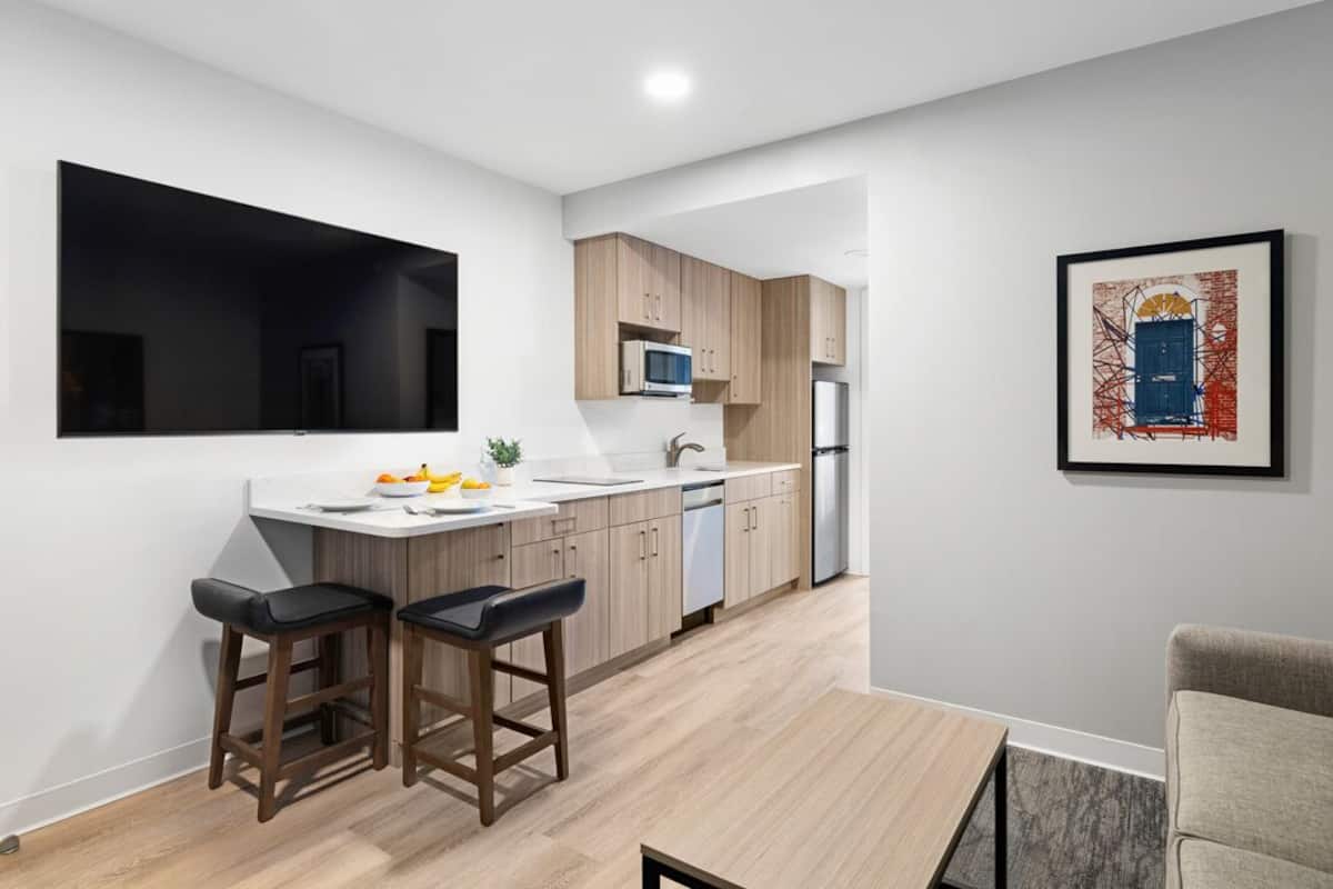 Una cocina moderna con microondas, lavamanos y una zona de comedor con taburetes.
