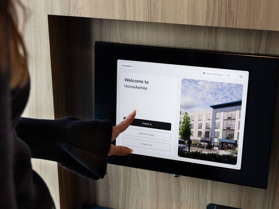 Um visor digital com mensagem de boas-vindas e opções para acesso ao quarto.