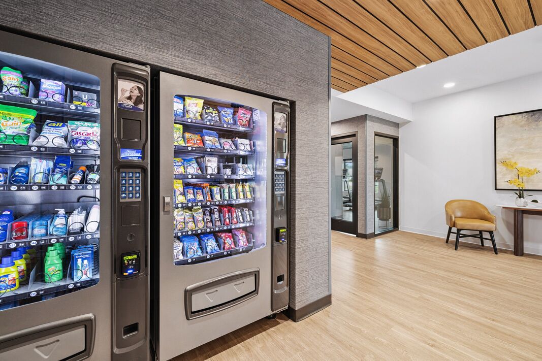Um hall de hotel moderno com máquinas de venda automática, teto de madeira e decoração minimalista.