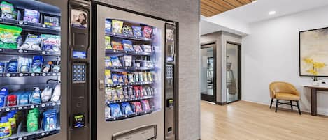 A modern hotel lobby with vending machines, a wooden ceiling, and a minimalist decor.