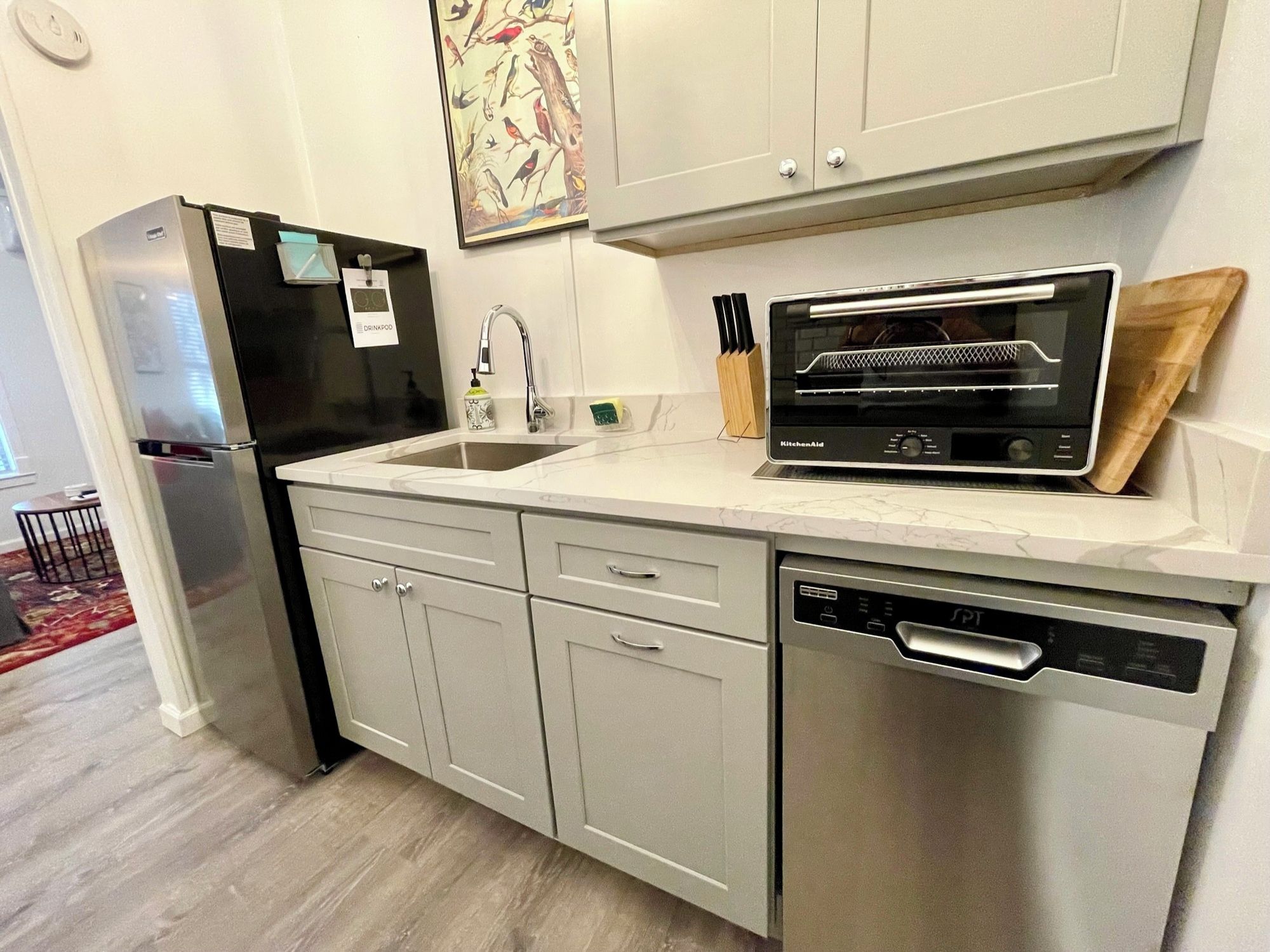 A modern kitchen with a stainless steel refrigerator, a built-in oven, a dishwasher, and a sink.