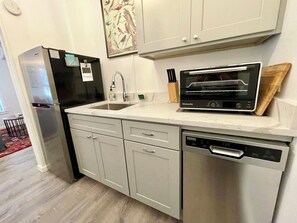 A modern kitchen with a stainless steel refrigerator, a built-in oven, a dishwasher, and a sink.