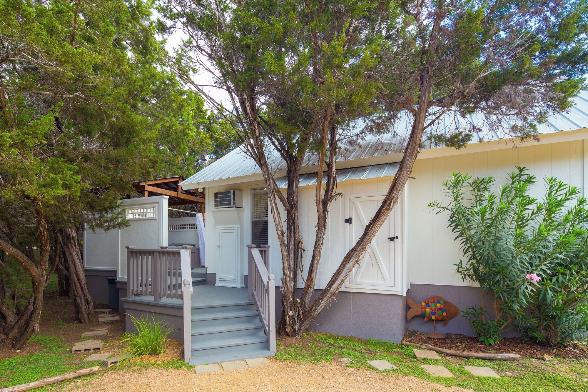 A residential property with a front porch, a staircase leading to the entrance, and a garden area with various plants.