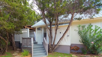 A residential property with a front porch, a staircase leading to the entrance, and a garden area with various plants.